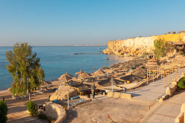 istock Panoramic view of beach Ras Umm El Sid. Beautiful sunrise over Red Sea with rocky shores, sandy beach with umbrellas and first rays of sun, Sharm El Sheikh, Egypt. Vacation, holiday concept 1424488788