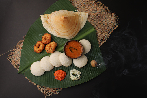 Group of South Indian food like Masala Dosa, Idli, Wada or vada, sambar, served over banana leaf with colourful coconut chutneys