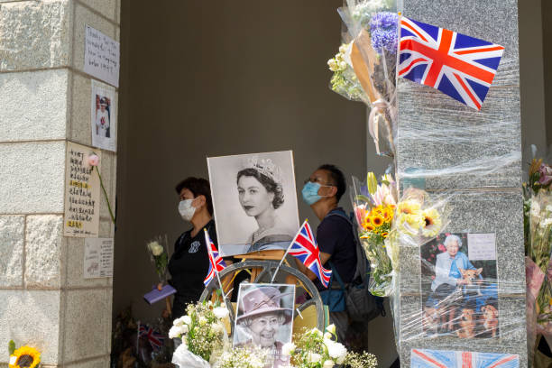 People gather next to flowers placed as a tribute outside the British Consulate in Hong Kong on  following the death of Britain's Queen Elizabeth II. September 16, 2022,Hong Kong.People gather next to flowers placed as a tribute outside the British Consulate in Hong Kong on  following the death of Britain's Queen Elizabeth II. elizabeth ii photos stock pictures, royalty-free photos & images