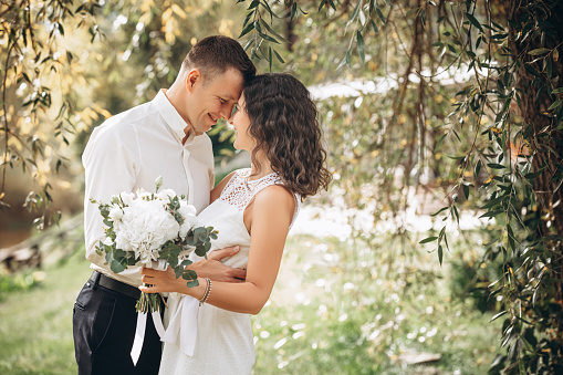 Beautiful happy couple married man and woman with a bouquet of flowers, portrait in nature