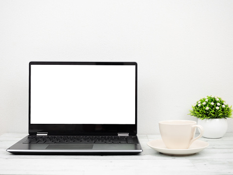 Laptop white screen with coffee cup and vase minimal on wooden table workspace concept
