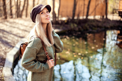 Portrait of a young happy woman tourist on a lake in the autumn forest. Forest Lake and Tourism