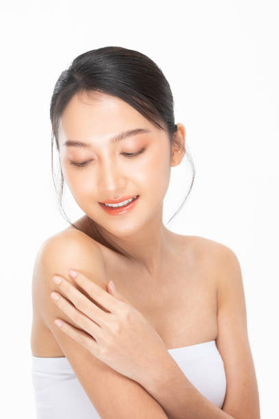 istock Wellness Beautiful Young Asian Woman Looking While Touching Shoulder feeling so happy and cheerful with healthy Clean and Fresh skin,isolated on white. Self care and Beauty Cosmetics Concept 1424508651