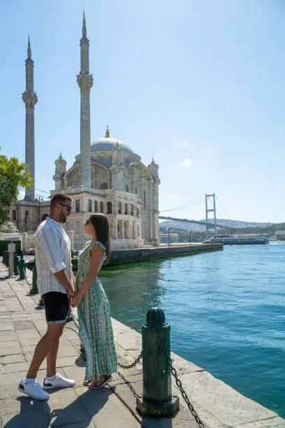 Photo of Couple in love gazing into each other's eyes with the ortakoy mosque and the famous istanbul bridge in the background.