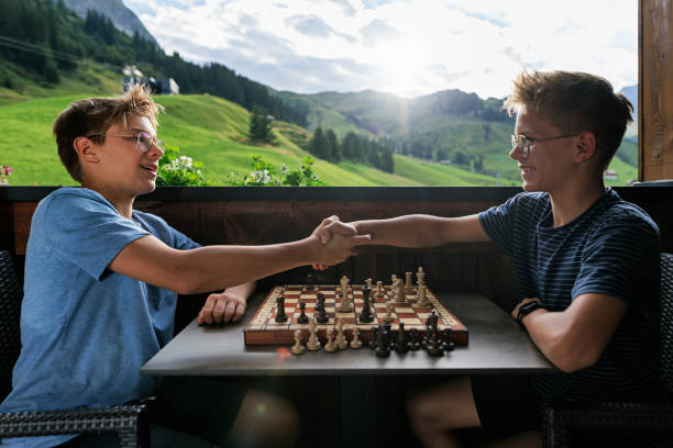Teenage boys playing chess on the balcony Teenage brothers playing chess on the balcony. Summer day in European Alps, Vorarlberg, Austria.
Shot with Canon R5 tie game stock pictures, royalty-free photos & images