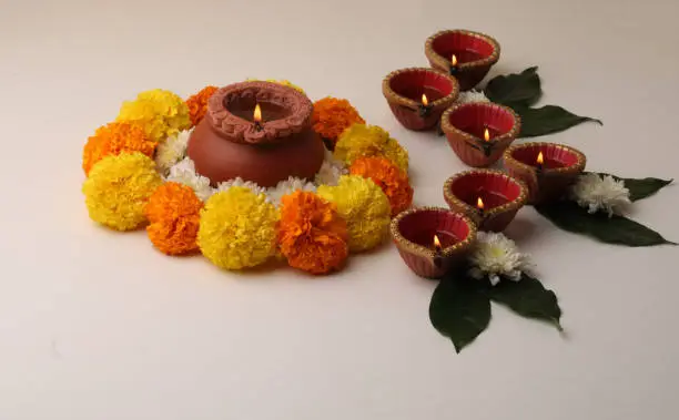 Flower Rangoli for Diwali or Pongal Festival made using Marigold or Zendu flowers and Clay Oil Lamp over redbackground. copy space.