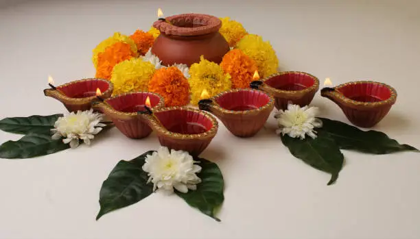 Flower Rangoli for Diwali or Pongal Festival made using Marigold or Zendu flowers and Clay Oil Lamp over redbackground. copy space.