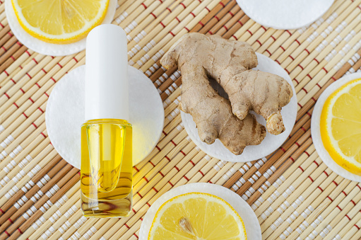 Small bottle with essential ginger oil (extract, tincture, infusion, perfume) and lemon extract. Aromatherapy, spa and herbal medicine ingredients. Copy space