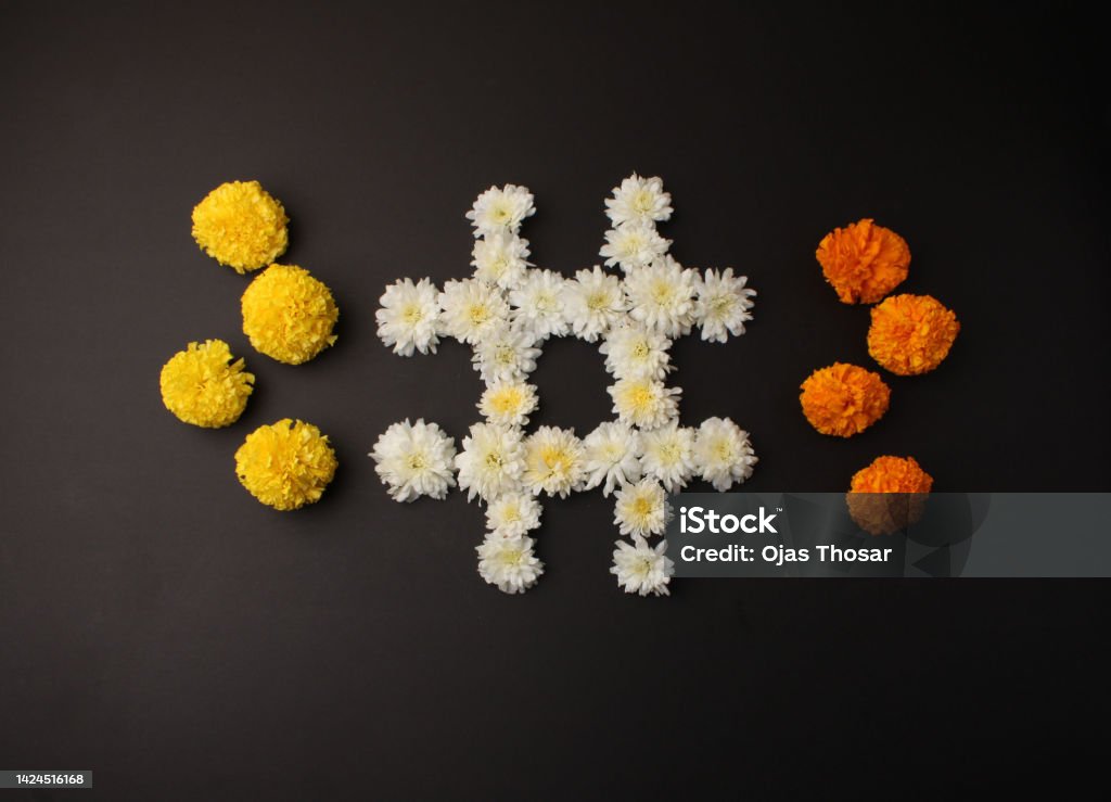 Flower Rangoli for Diwali or Pongal Festival made using Marigold or Zendu flowers and Clay Oil Lamp over black background. in tick tack toe game Marigold Stock Photo