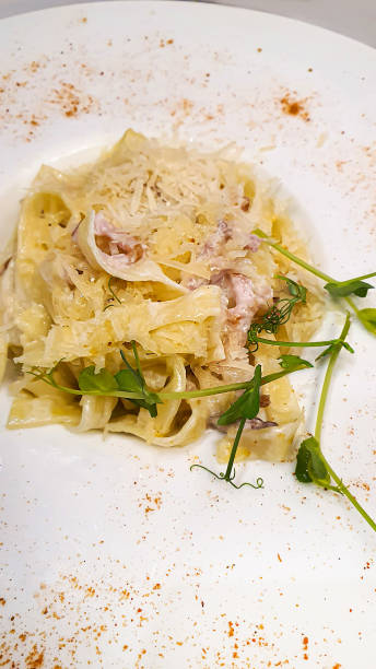 istock Pasta carbonara with ham and cheese. Garnished with pea sprouts. In a white plate. 1424519140
