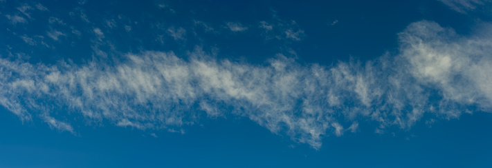 Stripe of cirrus clouds against the blue sky. Autumn. Web banner.