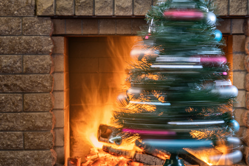A Christmas tree is spinning against the background of a burning fireplace in country house