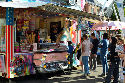 Leuven, Flemish-Brabant, Belgium - September 11, 2022: visitors fairground attractions in a line row to buy ice cream from a vintage ice cream shop with a part of a car, pink front of a Chevrolet car