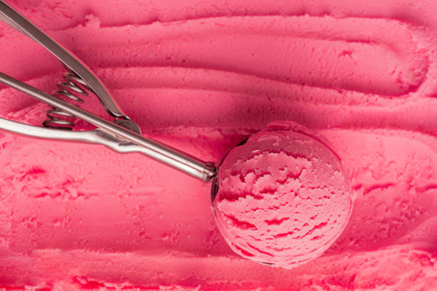 シャーベットのテクスチャー表面に金属スプーンを提供するピンクの甘い天然アイスクリームのスクープの上面図