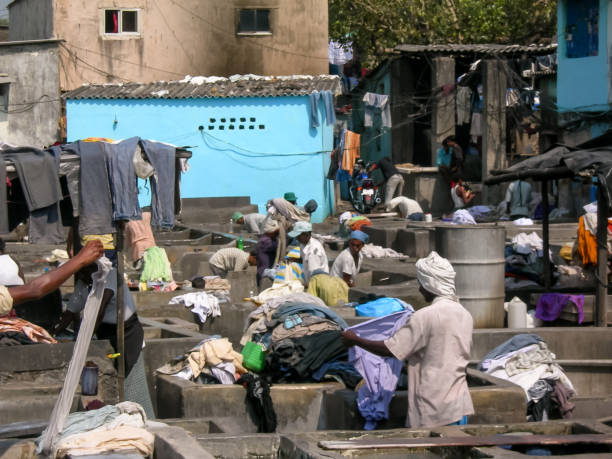 Mumbay, India - nov 01, 2005: dozens of laundromats, all men, work by hand washing all sorts of garments or fabrics in the tubs of the Dhobi Ghat district