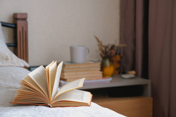 istock Old open book with yellow pages lies on a beige bed with pillows. 1424558586