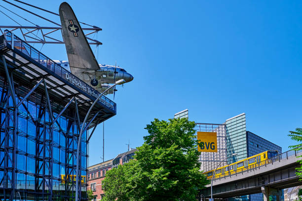 Berlin, Germany - July 17, 2022: Metro train operated by Berliner Verkehrsbetriebe (BVG) on a historic bridge. On the left you can see a historic aircraft from the German Museum of Technology.