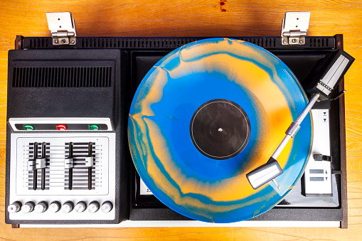 Vintage turntable vinyl record player with blue and orange vinyl on a table
