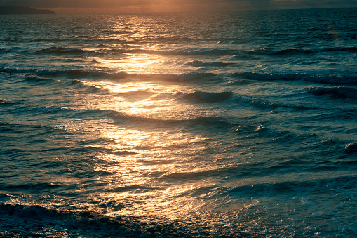 Warm setting sunshine in the waves off the Devon coast, UK