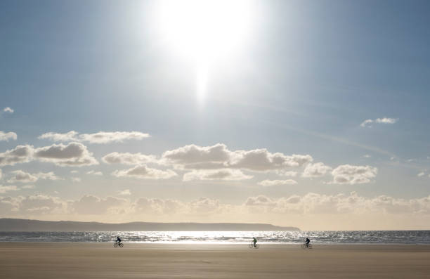 coastal de ciclismo - silhouette three people beach horizon - fotografias e filmes do acervo