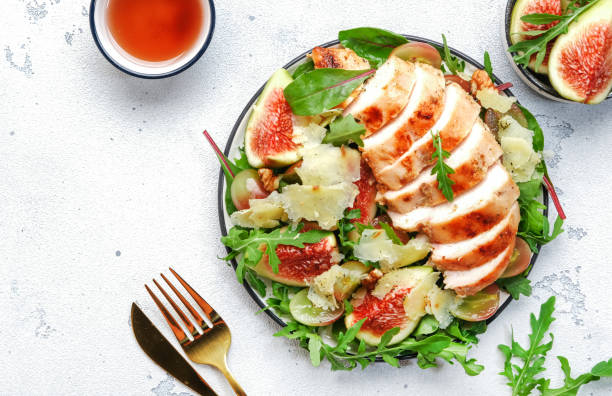 istock Grilled chicken fillet with fig, grape, arugula and chard salad. White kitchen table background, top view 1424577506
