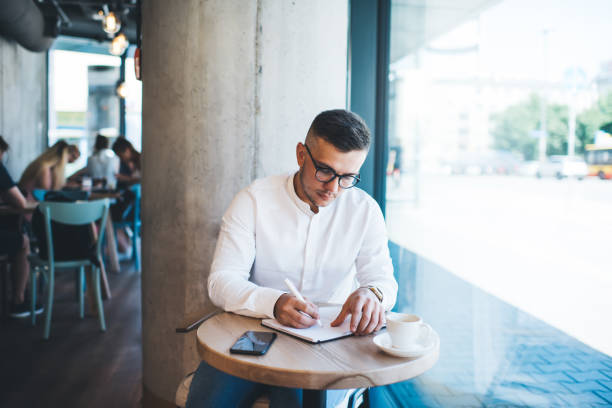istock Young man working with notes in contemporary cafe 1424583355