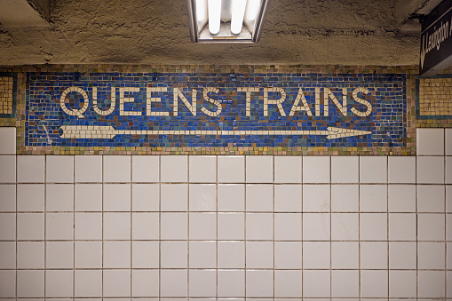 Manhattan, New York, NY, USA - July 15th 2022:  Sign at 5th Avenue Subway Station showing the direction to the trains bound for Queens