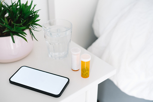 Pill bottles next to a smartphone on the nightstand