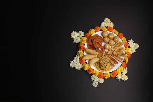 Diwali Rangoli or design made using Indian snacks/sweet and flowers. copy space.