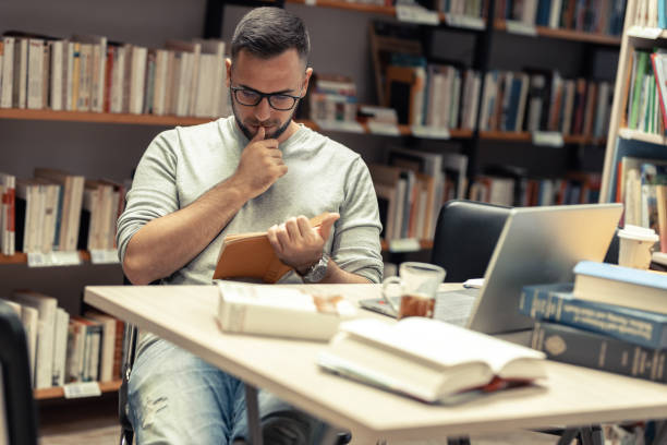 istock A male student studying in the campus library .He reads a book. 1424591743