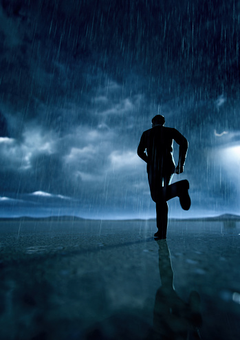 Hombre de traje negro corre en un desierto lluvioso con un cielo nublado. Renderizado 3D. photo
