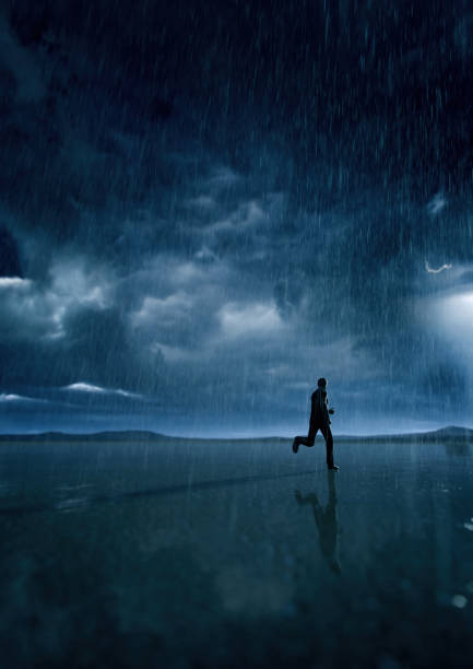 istock Man in black suit runs in rainy desert with a cloudy sky. 3D render. 1424592603