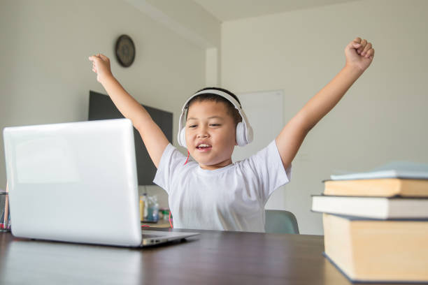 istock Young student distance learning virtual distance online class on video call virtual lesson, technology studying at home using laptop computer. Parent or tutor teaching child boy with remote education. 1424596986