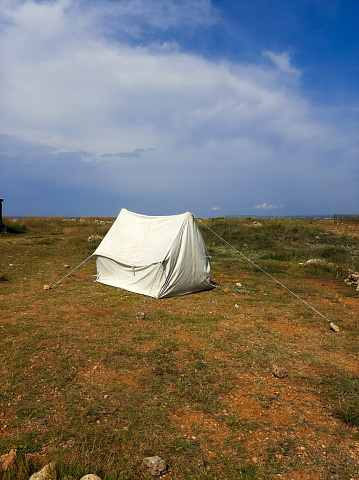 A marquee on the top of the cliff in a camping place near the sea. A traveling tent in a field against the sky in summer day. Outdoor and lifestyle, camping