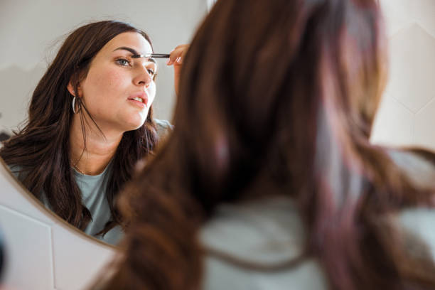 Woman fixing make-up in front of the bathroom mirror stock photo