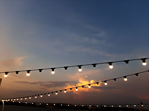 Bulb garland decoration against the sky in sunset time. Courtyard decor. Party decoration. Summer evening