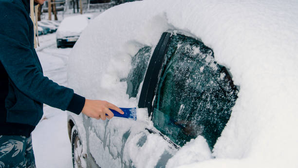 usuwanie lodu i śniegu ze szyby samochodowej za pomocą skrobaka do lodu - snow car window ice scraper zdjęcia i obrazy z banku zdjęć