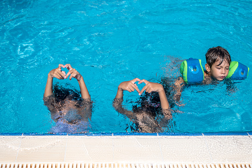 Happy little girls and brother enjoying in the pool