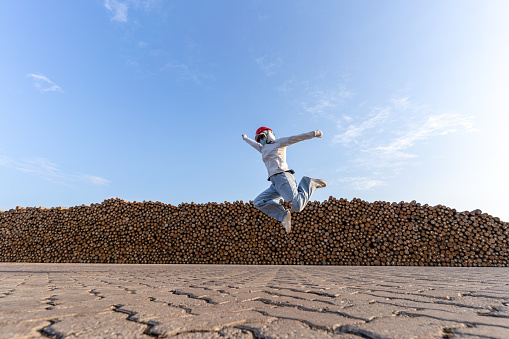 A masked woman jump in the wood stacking area