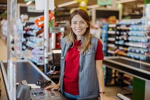 Portrait of smiling female cashier at the supermarket checkout
