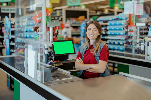 Portrait of smiling female cashier at the supermarket checkout