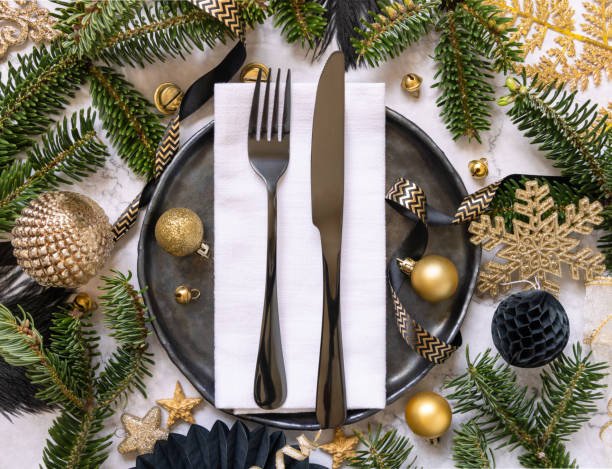 istock Black and golden Christmas table setting with decorations and fir tree branches top view 1424628638