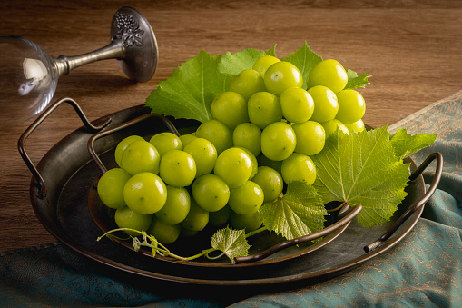 Green grapes in a tray on a wooden background