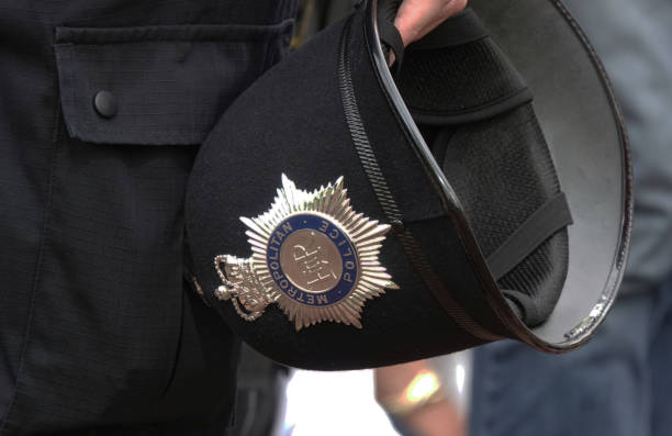 o capacete de um policial metropolitano segurado ao seu lado. - police helmet - fotografias e filmes do acervo