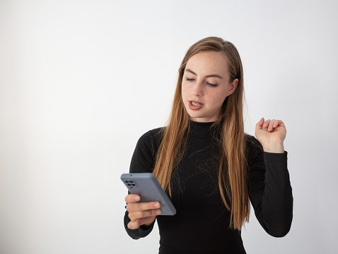 Blonde woman in black outfit looking at her cell phone.
White background.
Cute Russian girl.