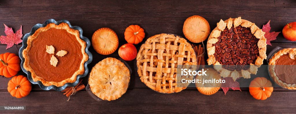 Assorted homemade fall pies. Top view table scene on a dark wood banner background. Assorted homemade fall pies. Pumpkin, apple and pecan. Top view table scene on a dark wood banner background. Thanksgiving - Holiday Stock Photo