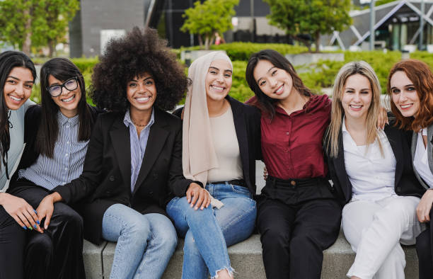 istock Young diverse business women sitting outdoor while smiling on camera 1424646214