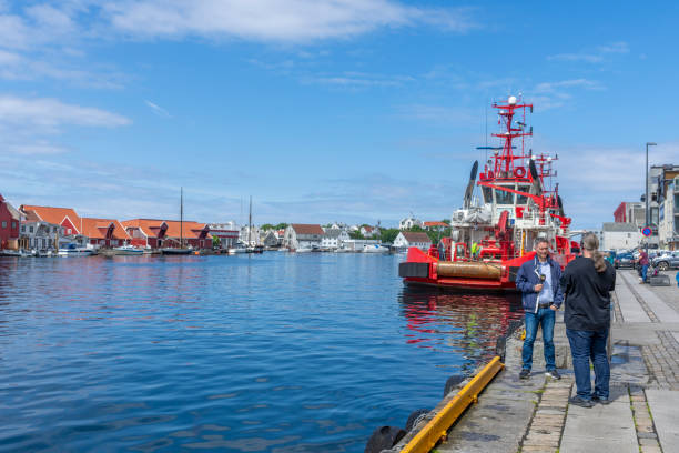 Haugesund Harbour and harbour side buildings, Norway. These are two coaster vessels moored in the harbour.  A Norwegian journalist is interviewing someone on the dock side.