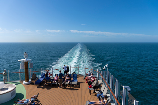 Ship deck of a ship in the Norwegian fjords, there are passengers watching the wake over the stern of the ship. Olden, Norway.