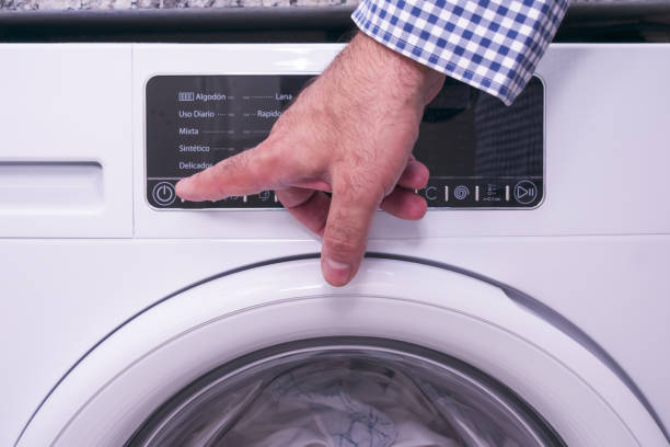istock Mature man presses power button of washing machine. 1424660317